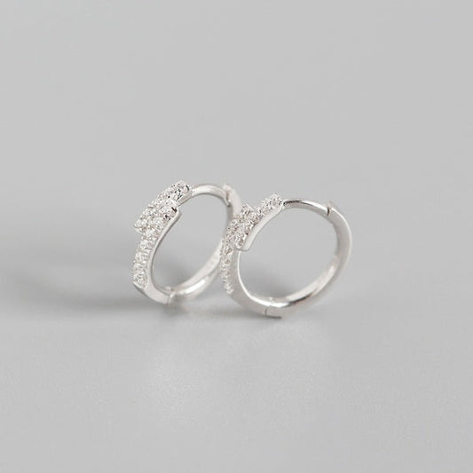 sterling silver hoops with cubic zirconia in an overlapping design on a white background