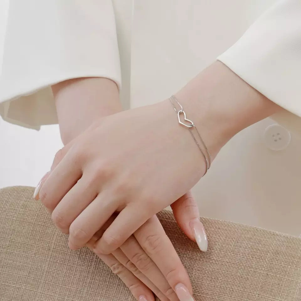 Sterling silver bracelet worn on a hand, featuring a delicate double chain and heart detail, perfect for teens and adults.