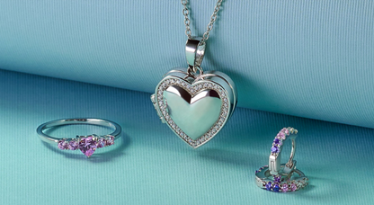 Children's jewelry including a sterling silver pink CZ heart ring, heart pendant, and colorful earrings on a blue background.