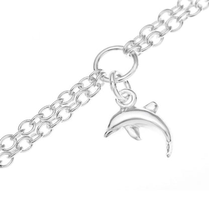 Close up of a dolphin charm on a silver children's double chain charm bracelet on a white background