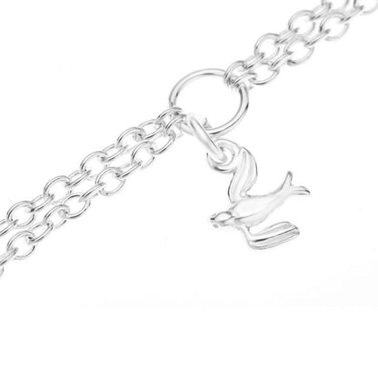 Close up of a hummingbird charm on a silver children's double chain charm bracelet on a white background
