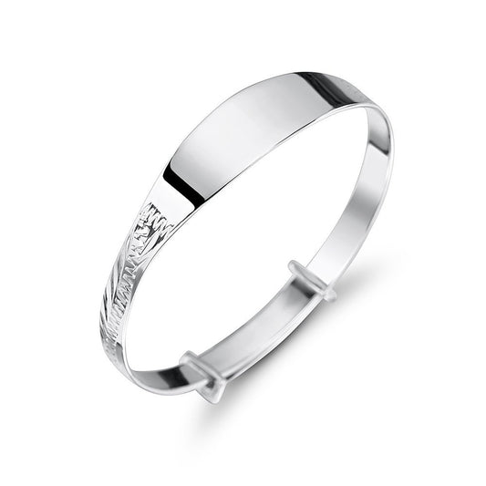 Sterling silver children’s expandable bangle bracelet with a polished, plain ID plate and a diamond-cut patterned section at one end, featuring two slider rings for an adjustable fit, shown on a white background.