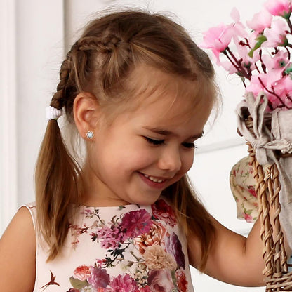 A little girl in a pink dress wearing a pair of sterling silver flower shaped stud earrings with sparkling clear cubic zirconia centres in her ears